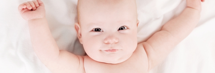 Nahaufnahme eines Babys, das glücklich aussieht und die Arme wegsteckt. - TOP-Kurs